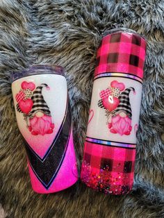 two pink and black plaid tumbles sitting on top of a fur rug next to each other