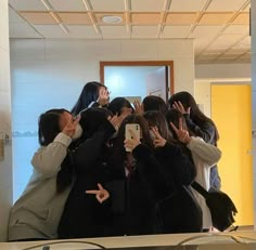 a group of women standing in front of a mirror taking pictures with their cell phones