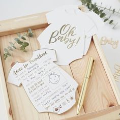 a wooden box with some baby clothes on it and a pen in the drawer next to it