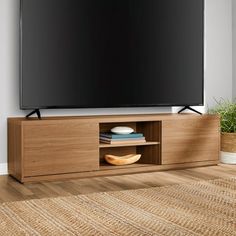 a flat screen tv sitting on top of a wooden entertainment center next to a potted plant