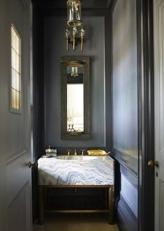 a hallway leading to a bedroom with a bed and chandelier hanging from the ceiling