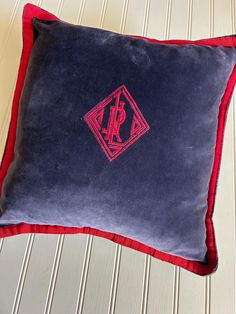 a blue and red pillow with a monogrammed r on it