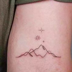 a small tattoo on the side of a woman's stomach, with mountains in the background