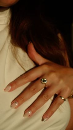 a close up of a person wearing rings on their fingers and holding onto her shirt