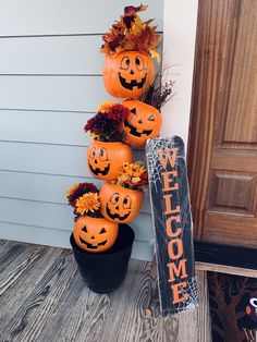 pumpkins and flowers are arranged on the front porch for halloween decorations, along with a welcome sign