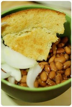 a green bowl filled with beans and bread