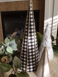 two christmas trees sitting on top of a table next to a fireplace