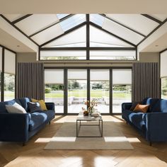 a living room filled with blue couches next to a white coffee table and windows