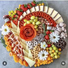 a platter filled with lots of different types of cheeses and fruit on top of each other