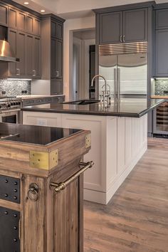 a large kitchen with an island in the middle and stainless steel appliances on both sides