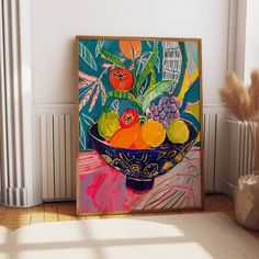 a painting is displayed on the wall next to a potted plant and vase with fruit in it