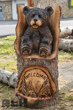 a bear statue sitting on top of a tree stump with the words welcome to me carved into it