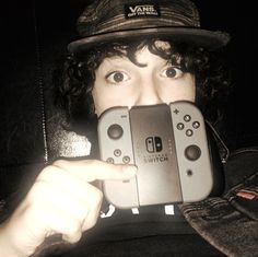 a person holding up a nintendo wii game controller to take a photo with their phone