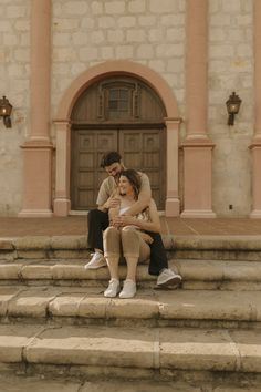 a man and woman sitting on steps in front of a building with a door that leads to another building