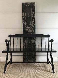 a black bench sitting in front of a white wall