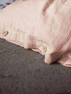 a pillow that is laying on the ground next to a blanket with buttons in it