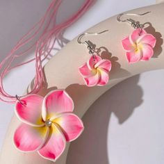 three pink flowers are hanging from earrings