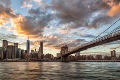 the city skyline is seen from across the water at sunset with clouds in the sky