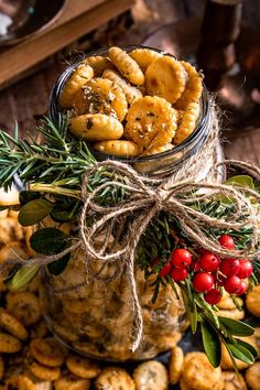 a glass jar filled with cookies on top of a pile of crackers and berries