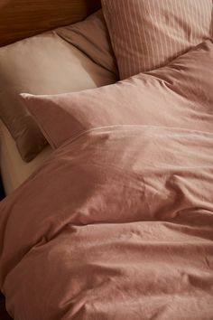 an unmade bed with pink sheets and pillows