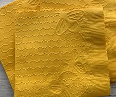 three pieces of yellow knitted fabric sitting next to each other on top of a wooden table