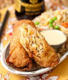 two fried food items on a plate with chopsticks and dipping sauce next to it