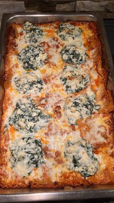 a square casserole with cheese and spinach on it in a metal pan