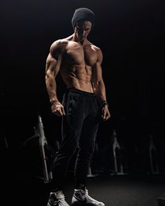 a shirtless man standing in the dark with his hands on his hips and looking down