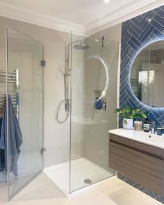 a bathroom with a walk in shower next to a white sink and mirror on the wall