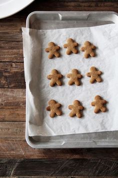 several cookies are arranged in the shape of people on a sheet of wax paper next to a white plate