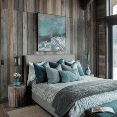 a bedroom with wood paneling and teal pillows on the bed, along with a large window