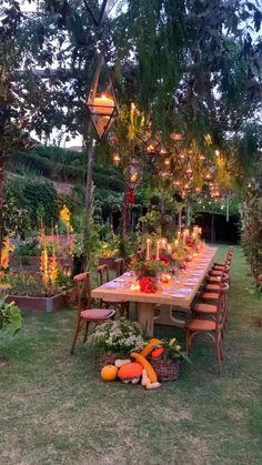 an outdoor dining table surrounded by flowers and candles