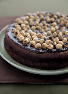 a chocolate cake topped with nuts on top of a white plate