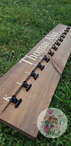 a wooden sign with black letters on it in the middle of some grass and flowers