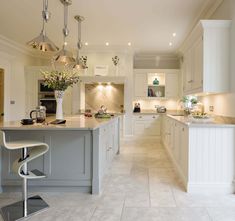 a large kitchen with white cabinets and an island in the middle is lit by pendant lights