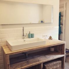 a bathroom sink sitting under a mirror next to a shelf with baskets on top of it