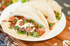 three shredded meat tacos on a white plate