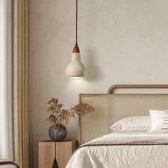 a bed with white sheets and pillows next to a lamp hanging from the ceiling above it