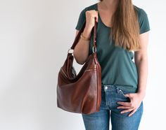 The hobo style bag was made 100% from highest quality full-grain italian leather. It can be worn both in crook of the elbow (short handle) as well as over the shoulder (adjustable long shoulder strap). The handbag is featured with a top zip. It is fitted with three zipped pockets: large at the front, smaller at the back and double in the inside, there is also a space to store a mobile phone. The bottom is stiffened. Fits easily A4 format (US Lettel format) and is very roomy, therefore it will be Natural Leather Bag, Slouchy Tote, Brown Crossbody Bag, Shoulder Bag Brown, Brown Leather Handbags, Brown Crossbody, Hobo Style, Leather Bag Women, Leather Hobo Bag