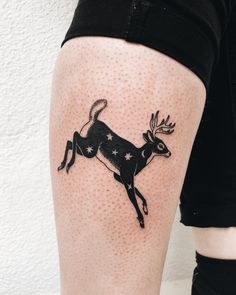 a tattoo on the leg of a woman with a deer and stars in its antlers