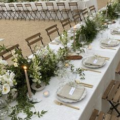 a long table set with place settings and flowers