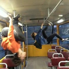 two people are hanging upside down on the bus while another person is jumping in the air