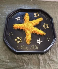 a black tray with writing on it that says,'little star'and an image of a cross made out of string