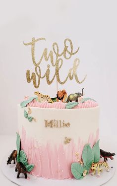 a cake decorated with pink and gold frosting, topped with an animal themed topper