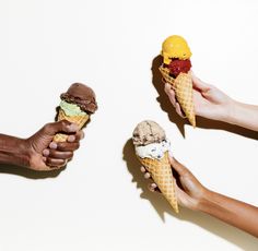 three people holding ice cream cones in their hands