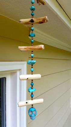 a wind chime hanging from the side of a house with blue beads on it