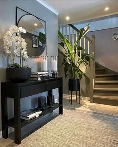 a living room with a black table and mirror on the wall next to a plant