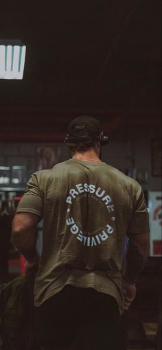 a man wearing a green shirt with the words pressure british printed on it is walking through a building