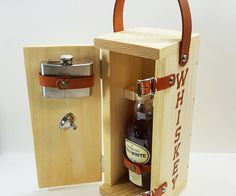 an open wooden box with a bottle in it and a leather strap around the bottom