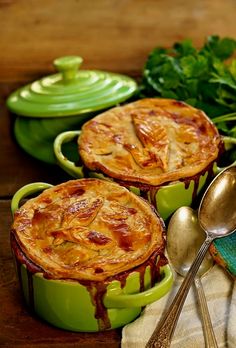 three pot pies sitting next to each other on top of a wooden table with spoons